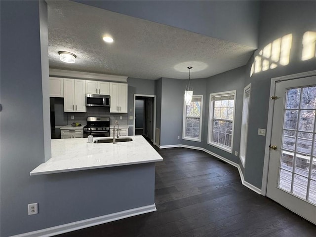 kitchen with sink, stainless steel appliances, decorative light fixtures, a textured ceiling, and white cabinets