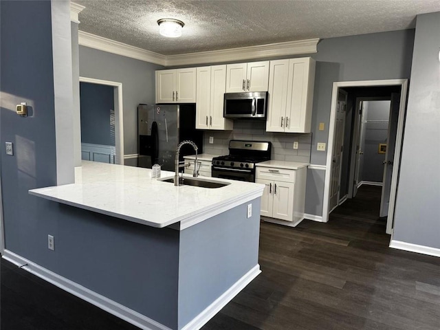 kitchen featuring sink, tasteful backsplash, white cabinetry, kitchen peninsula, and stainless steel appliances