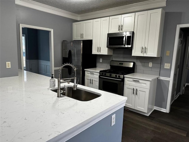 kitchen with appliances with stainless steel finishes, backsplash, a textured ceiling, sink, and white cabinetry