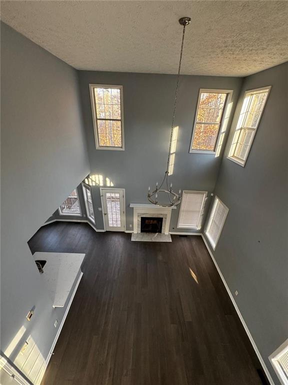 unfurnished living room with a fireplace, a textured ceiling, dark hardwood / wood-style flooring, and a towering ceiling