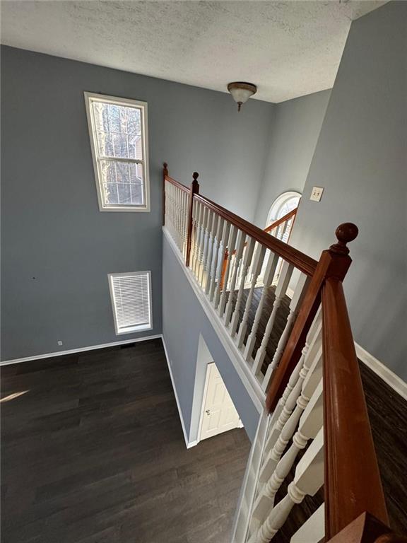 stairs with hardwood / wood-style floors and a textured ceiling