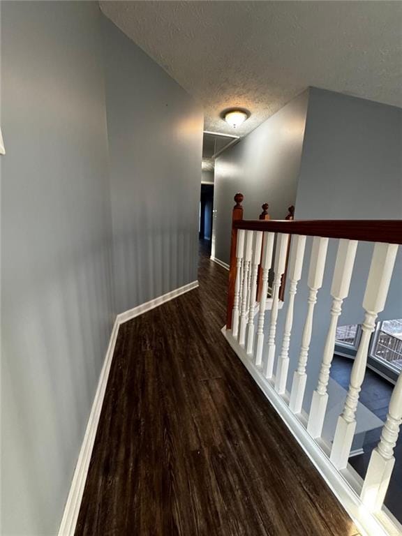 corridor with a textured ceiling and dark hardwood / wood-style floors