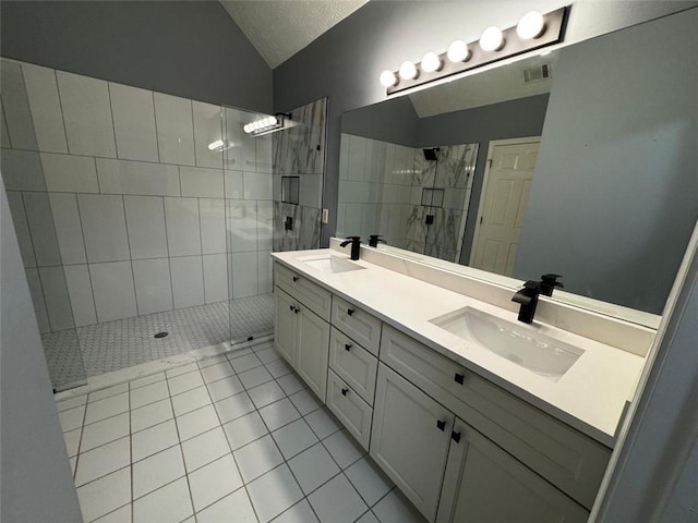 bathroom featuring tile patterned floors, a tile shower, vanity, a textured ceiling, and lofted ceiling