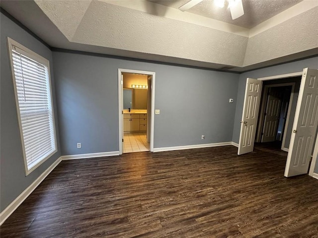 unfurnished bedroom with dark hardwood / wood-style flooring, a raised ceiling, and ceiling fan