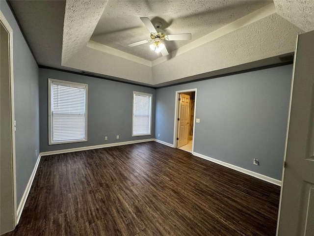 unfurnished bedroom with wood-type flooring, a textured ceiling, a raised ceiling, and ceiling fan