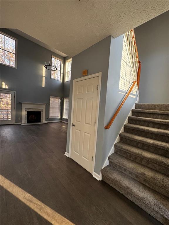 staircase with a textured ceiling, hardwood / wood-style floors, a high ceiling, and an inviting chandelier