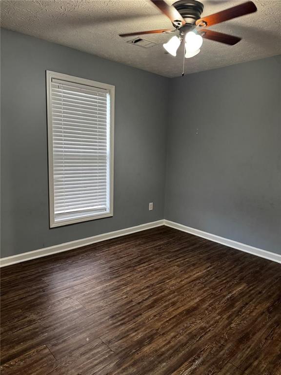 unfurnished room featuring a textured ceiling, ceiling fan, and dark wood-type flooring