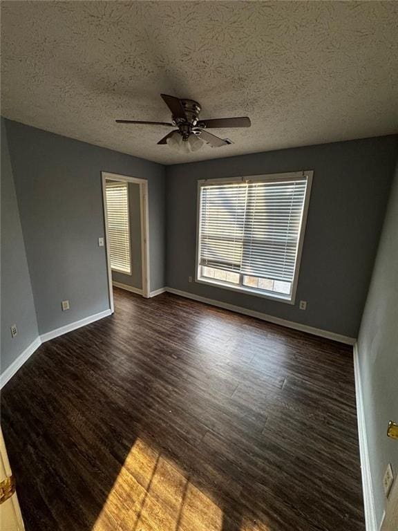 empty room with ceiling fan, dark wood-type flooring, and a textured ceiling