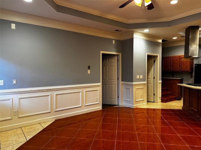 tiled spare room featuring a tray ceiling, crown molding, and ceiling fan