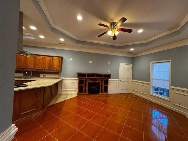 unfurnished living room featuring dark tile patterned flooring, a raised ceiling, ceiling fan, and ornamental molding