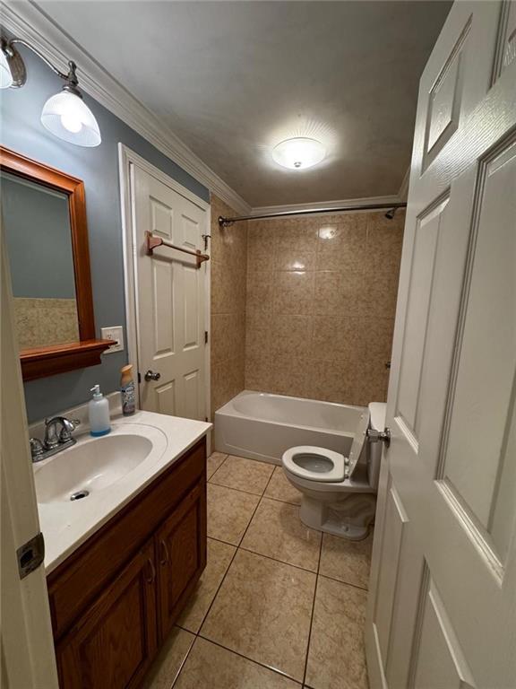 full bathroom with tile patterned flooring, ornamental molding, toilet, vanity, and tiled shower / bath