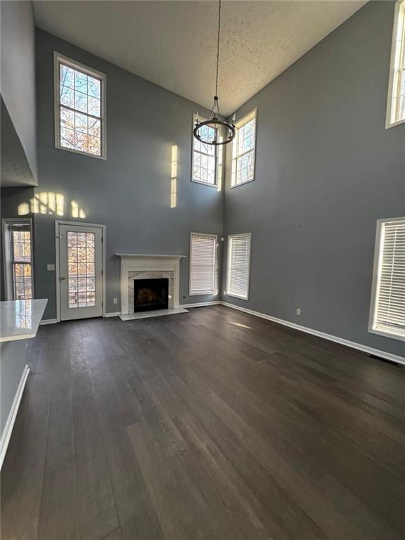 unfurnished living room featuring a fireplace, a high ceiling, plenty of natural light, and dark wood-type flooring