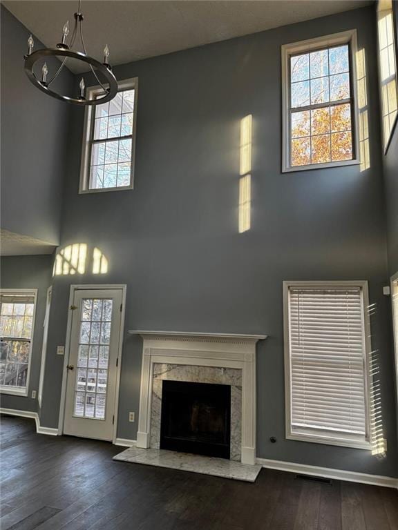 unfurnished living room with a fireplace, dark hardwood / wood-style flooring, a towering ceiling, and a chandelier