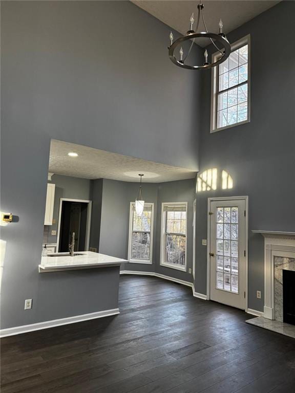 interior space with a high end fireplace, sink, a towering ceiling, dark hardwood / wood-style flooring, and a chandelier