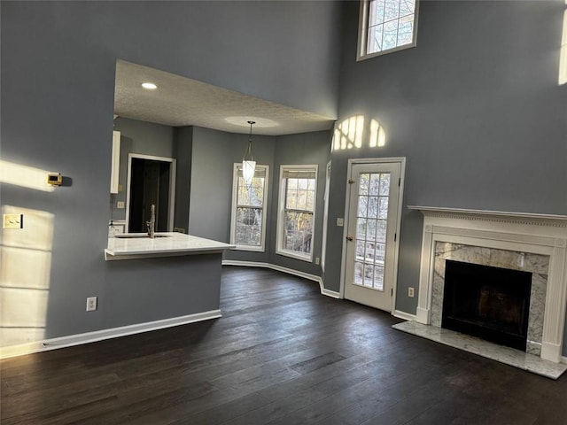 unfurnished living room featuring a fireplace, dark wood-type flooring, a high ceiling, and sink