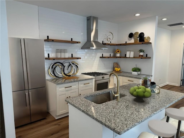 kitchen featuring white gas range, open shelves, freestanding refrigerator, a sink, and wall chimney range hood