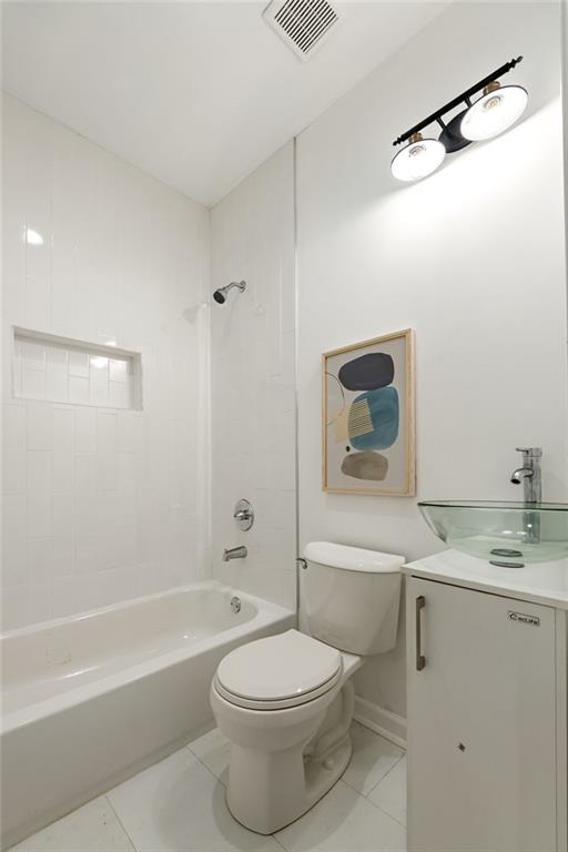 bathroom with baseboards, visible vents, toilet, shower / bathtub combination, and vanity