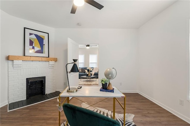 office area featuring baseboards, a fireplace, a ceiling fan, and dark wood-style flooring