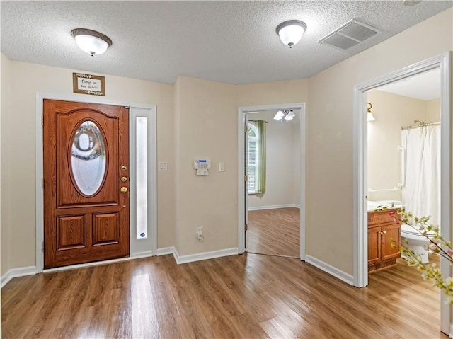 foyer entrance with light hardwood / wood-style floors and a textured ceiling