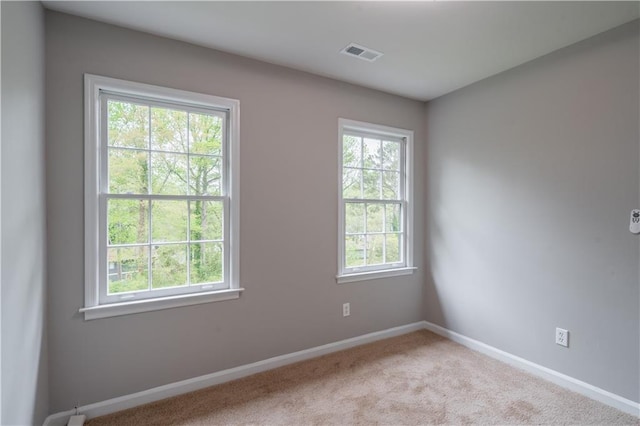 unfurnished room with baseboards, visible vents, a healthy amount of sunlight, and carpet
