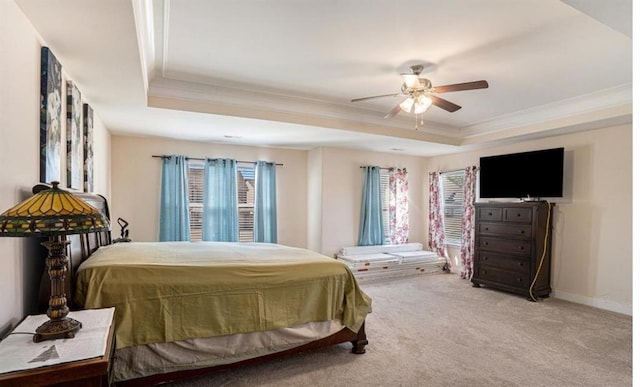 bedroom with ceiling fan, light colored carpet, a tray ceiling, and ornamental molding