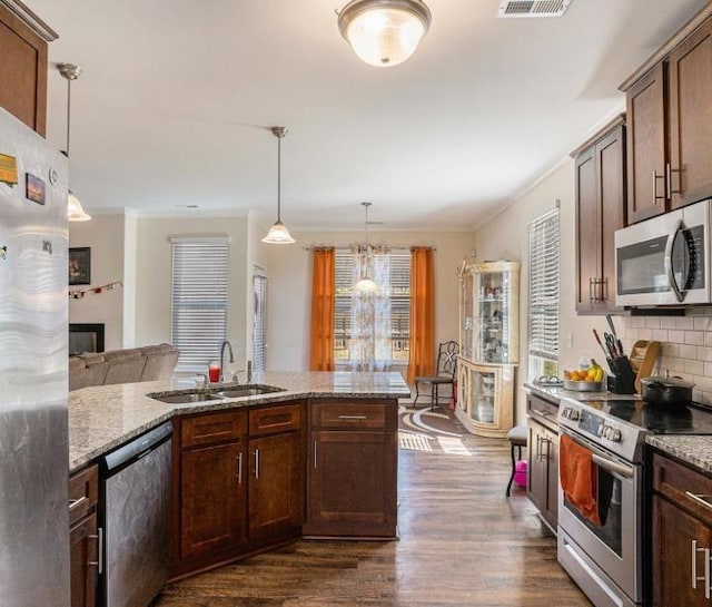 kitchen featuring pendant lighting, sink, stainless steel appliances, dark hardwood / wood-style floors, and light stone countertops