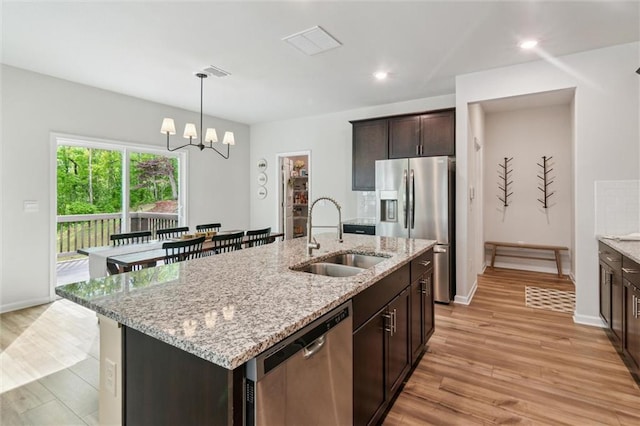 kitchen featuring a sink, stainless steel appliances, light wood-style flooring, and dark brown cabinets