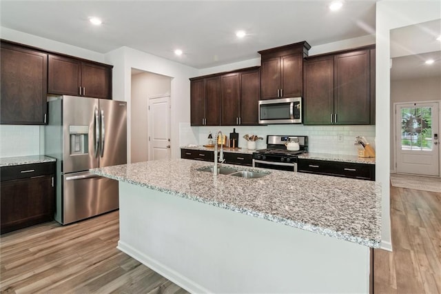 kitchen with a sink, appliances with stainless steel finishes, backsplash, and dark brown cabinets
