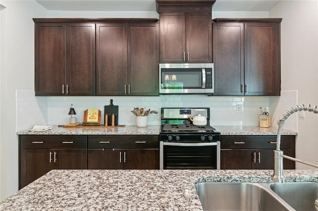 kitchen featuring light stone countertops, appliances with stainless steel finishes, and a sink