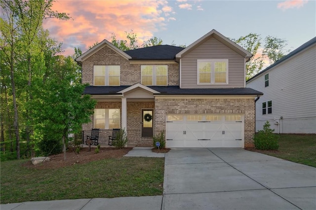 craftsman-style home with covered porch, brick siding, concrete driveway, an attached garage, and a yard