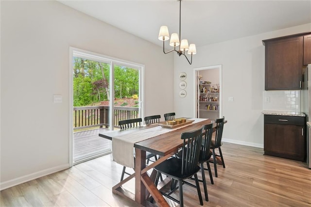 dining room with baseboards, an inviting chandelier, and light wood finished floors