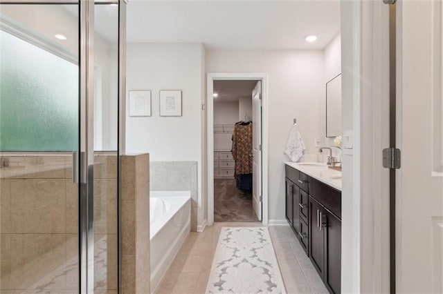 full bath featuring tile patterned flooring, vanity, a shower stall, a spacious closet, and a garden tub