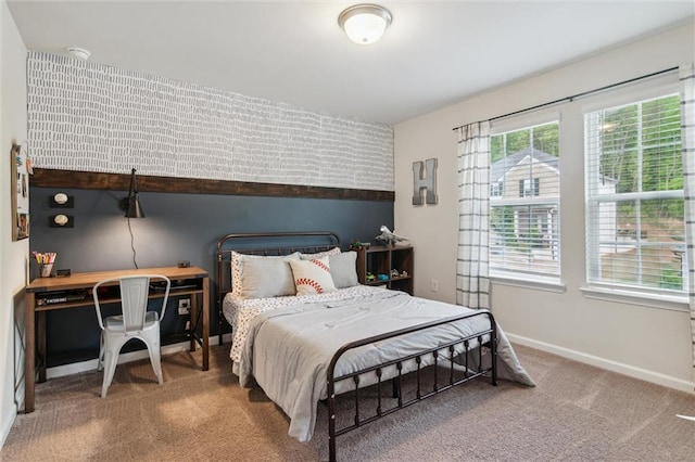 bedroom featuring baseboards, an accent wall, and carpet flooring