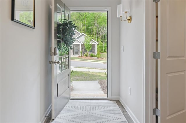 doorway to outside featuring baseboards and wood finished floors