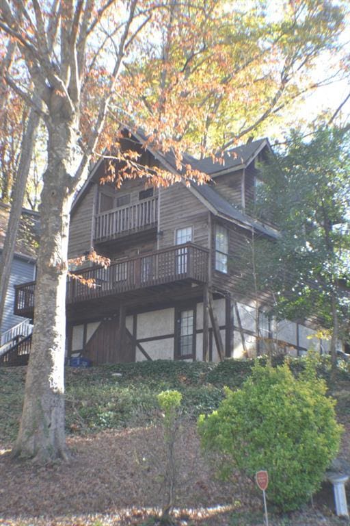 rear view of house with a wooden deck and a balcony