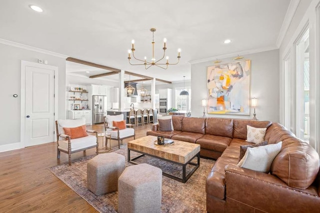 living room featuring wood-type flooring, ornamental molding, and a notable chandelier