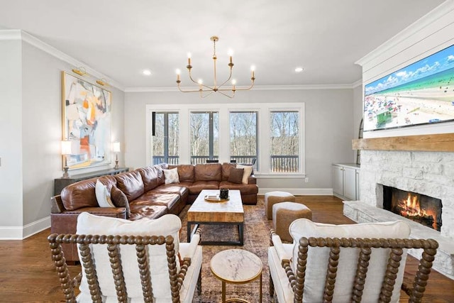 living room with crown molding, a stone fireplace, and a chandelier