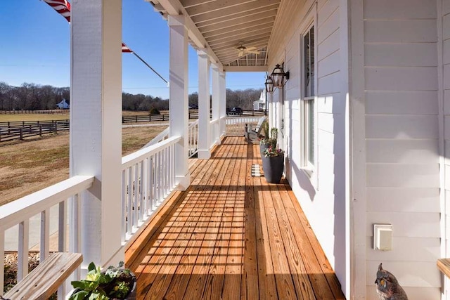 wooden terrace with a rural view, ceiling fan, and a porch