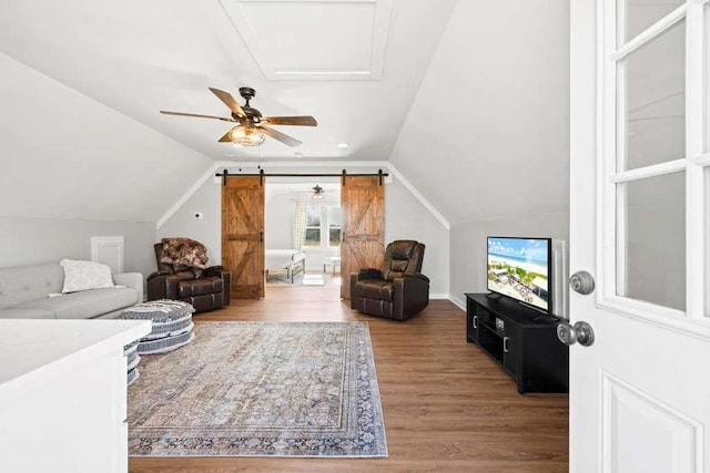 living room featuring hardwood / wood-style floors, vaulted ceiling, and a barn door