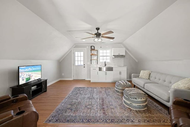 living room with hardwood / wood-style flooring, vaulted ceiling, sink, and ceiling fan