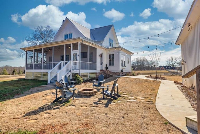 rear view of house with an outdoor fire pit and a sunroom