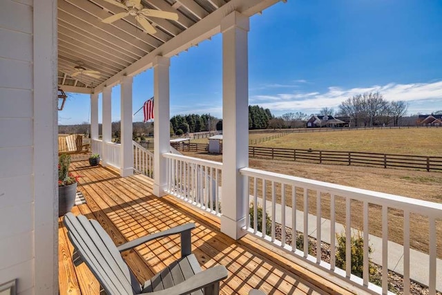 wooden terrace featuring ceiling fan, a porch, and a rural view