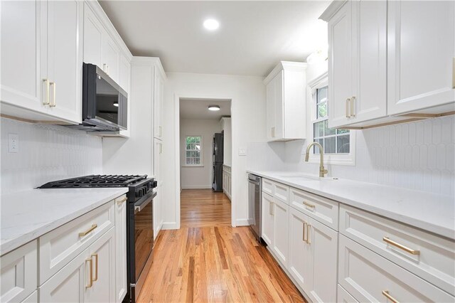 3480 Mount Olive Rd, Atlanta, GA 30344 - kitchen featuring black appliances, a sink, light wood-style floors, white cabinets, and baseboards