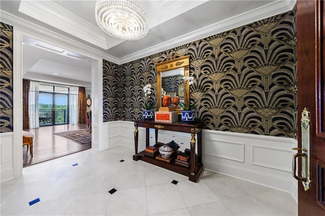 tiled entryway with a raised ceiling, a notable chandelier, and crown molding