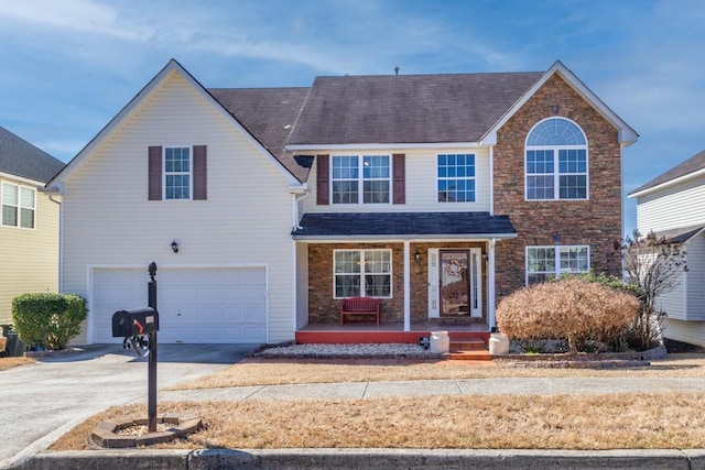 traditional home with covered porch, concrete driveway, a shingled roof, and a garage