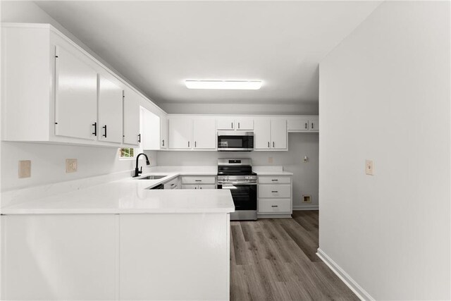 60 Weeping Willow Ln, Dawsonville, GA 30534 - kitchen with stainless steel appliances, a sink, a peninsula, light wood-type flooring, and white cabinets