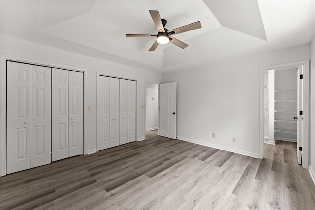 60 Weeping Willow Ln, Dawsonville, GA 30534 - unfurnished bedroom with a raised ceiling, two closets, wood finished floors, baseboards, and ceiling fan