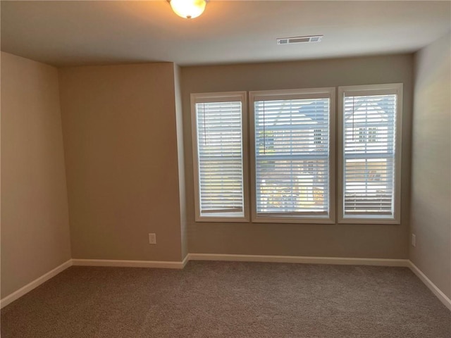 spare room featuring carpet floors, visible vents, and baseboards