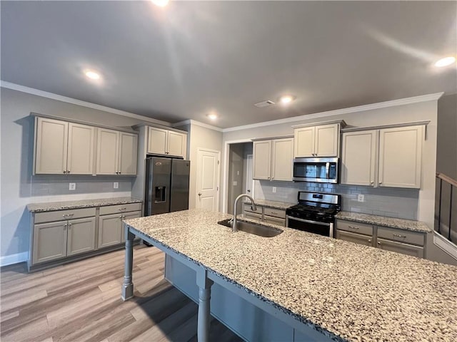 kitchen with crown molding, a sink, a breakfast bar, stainless steel appliances, and light stone countertops