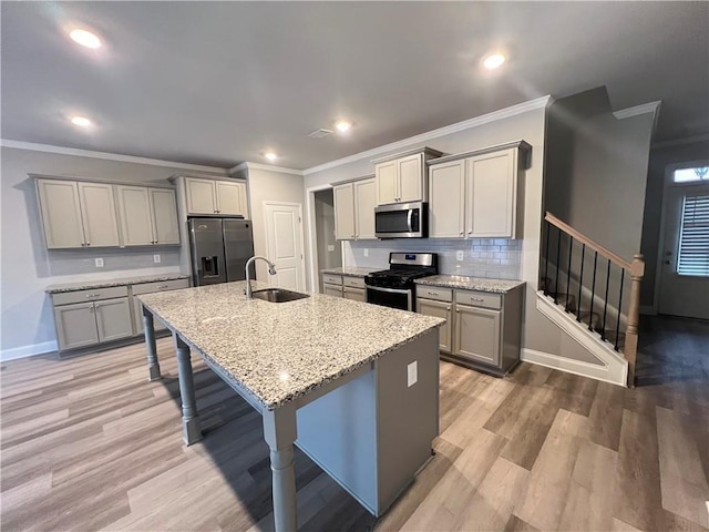 kitchen featuring gray cabinets, light stone counters, appliances with stainless steel finishes, ornamental molding, and a sink